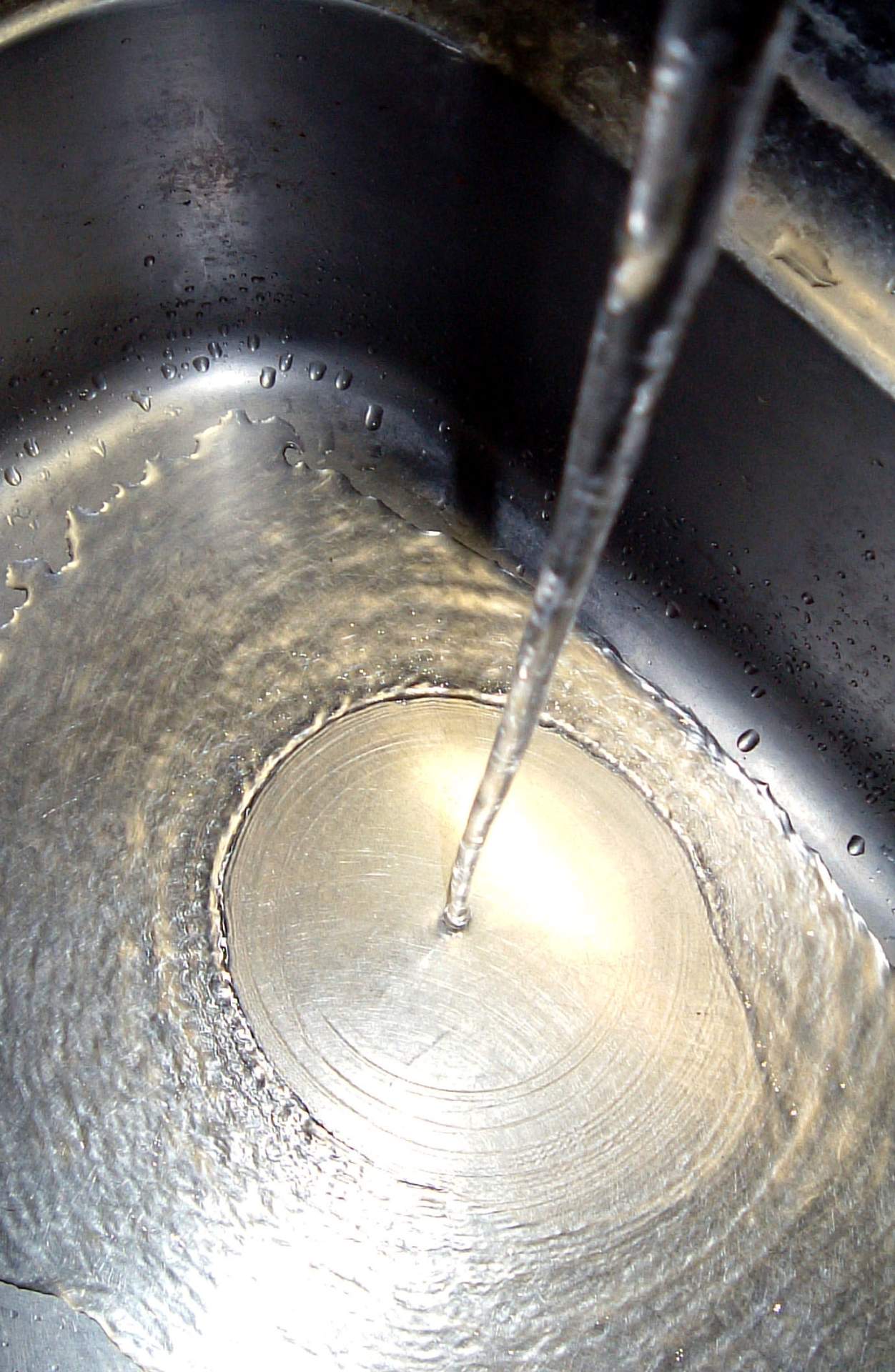 Abb. 3: Schiessende Strömung und der sie kreisförmig umgebende hydraulische Sprung in einem Waschbecken; Quelle: Wikipedia